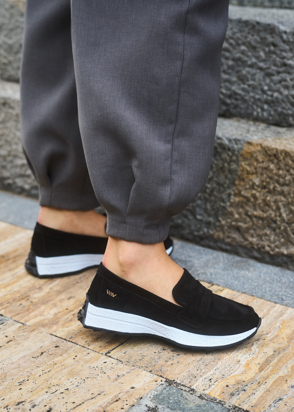 Close-up of Modena black suede slip-on loafers with white soles, styled with grey trousers — Viscata casual comfort shoes detail shot.
