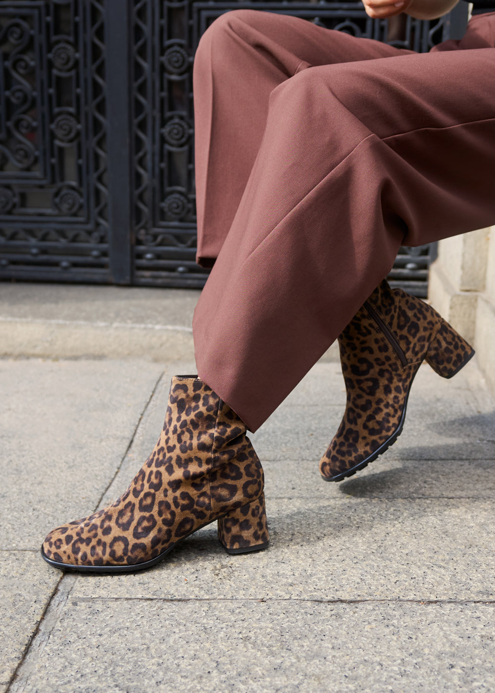 Close-up of woman wearing leopard-print ankle boots paired with brown tailored trousers — Viscata Barcelona’s bold and modern take on fall footwear.