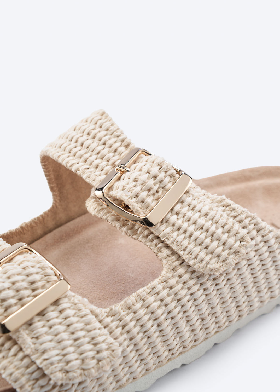 Close-up of a woven raffia slide sandal with buckle detail.