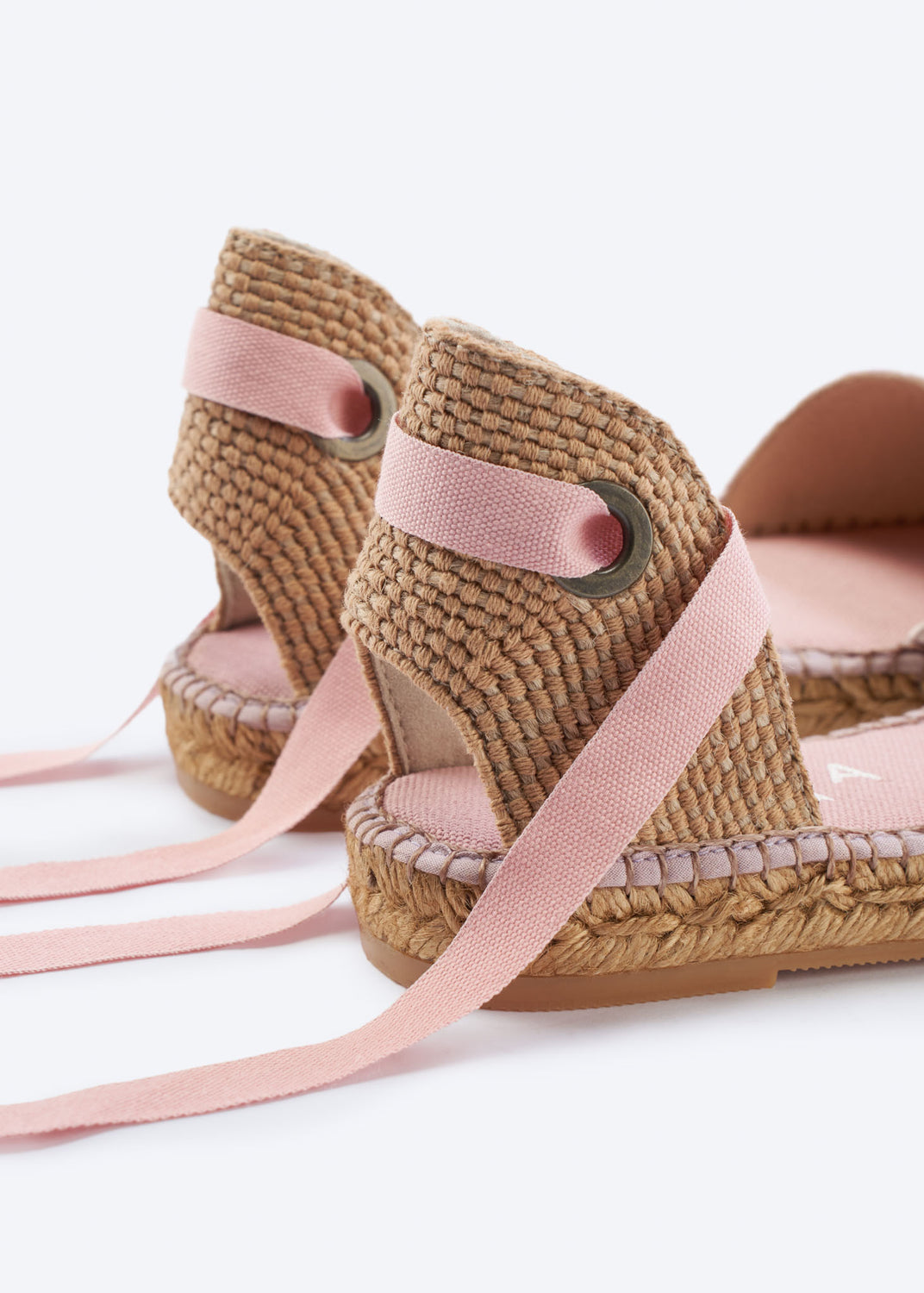 Close-up of daisy pink espadrille heel with woven texture and wraparound ankle ties.