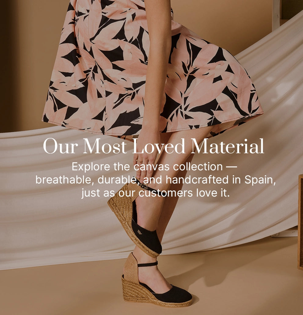 Woman wearing black canvas wedge espadrilles with ankle straps, styled with a floral skirt, showcasing Viscata’s handcrafted canvas collection; breathable, durable, and made in Spain