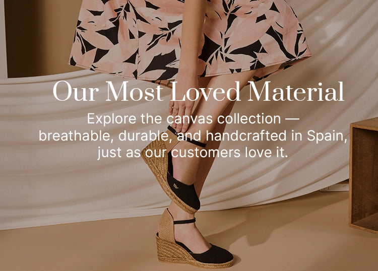 Woman wearing black canvas high wedge espadrilles with ankle straps, styled with a floral skirt, showcasing Viscata’s handcrafted canvas collection; breathable, durable, and made in Spain