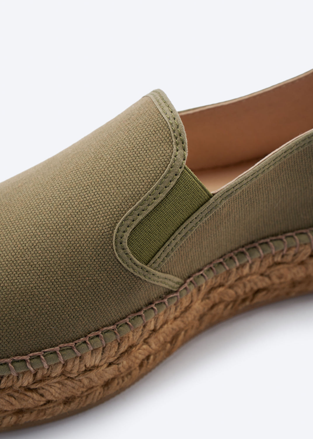 Close-up of olive green espadrille flat with side gore detail and a natural braided jute sole, handcrafted in Spain