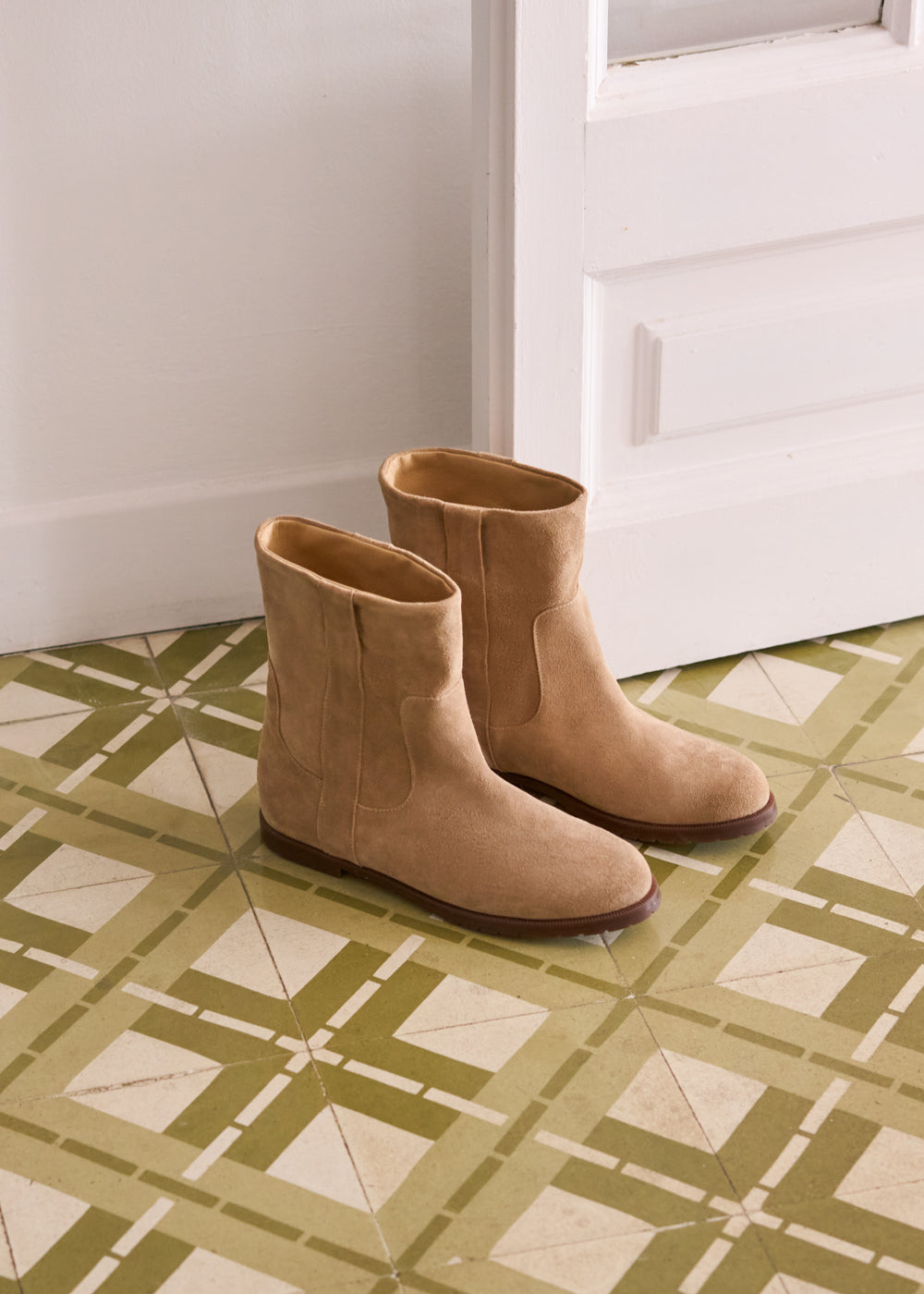 Pair of Cremona tan suede ankle boots placed on patterned tile flooring — Viscata Fall collection, handcrafted in soft suede for a timeless, versatile look.