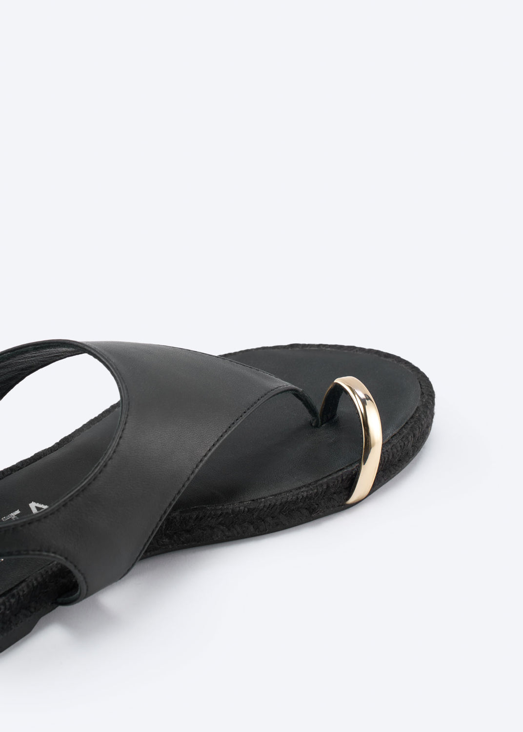 Close-up of a black leather thong sandal with gold-tone detail.
