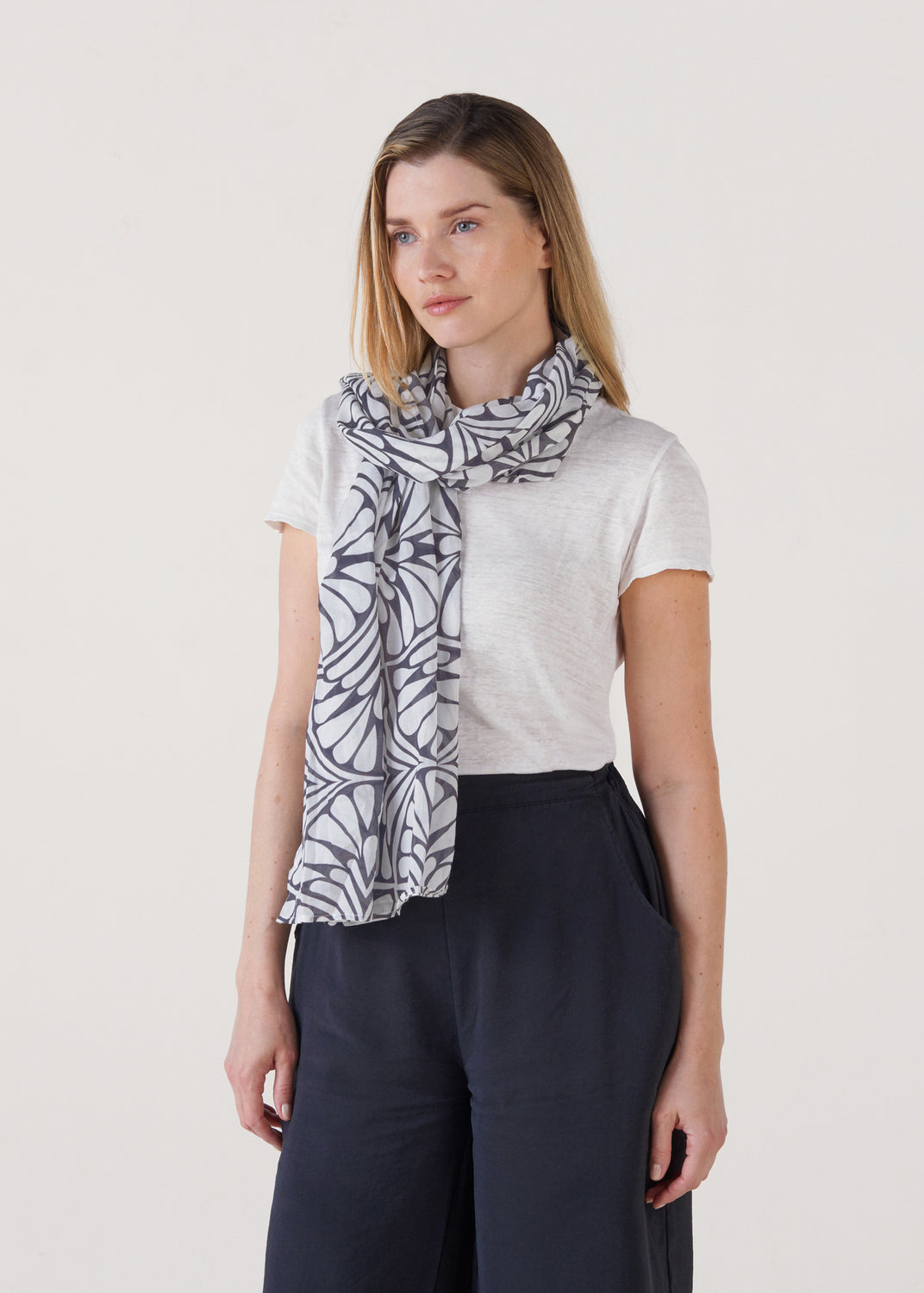 Studio portrait of a model wearing the Blue Palms cotton foulard scarf wrapped at the neck with the patterned ends draped down the front.