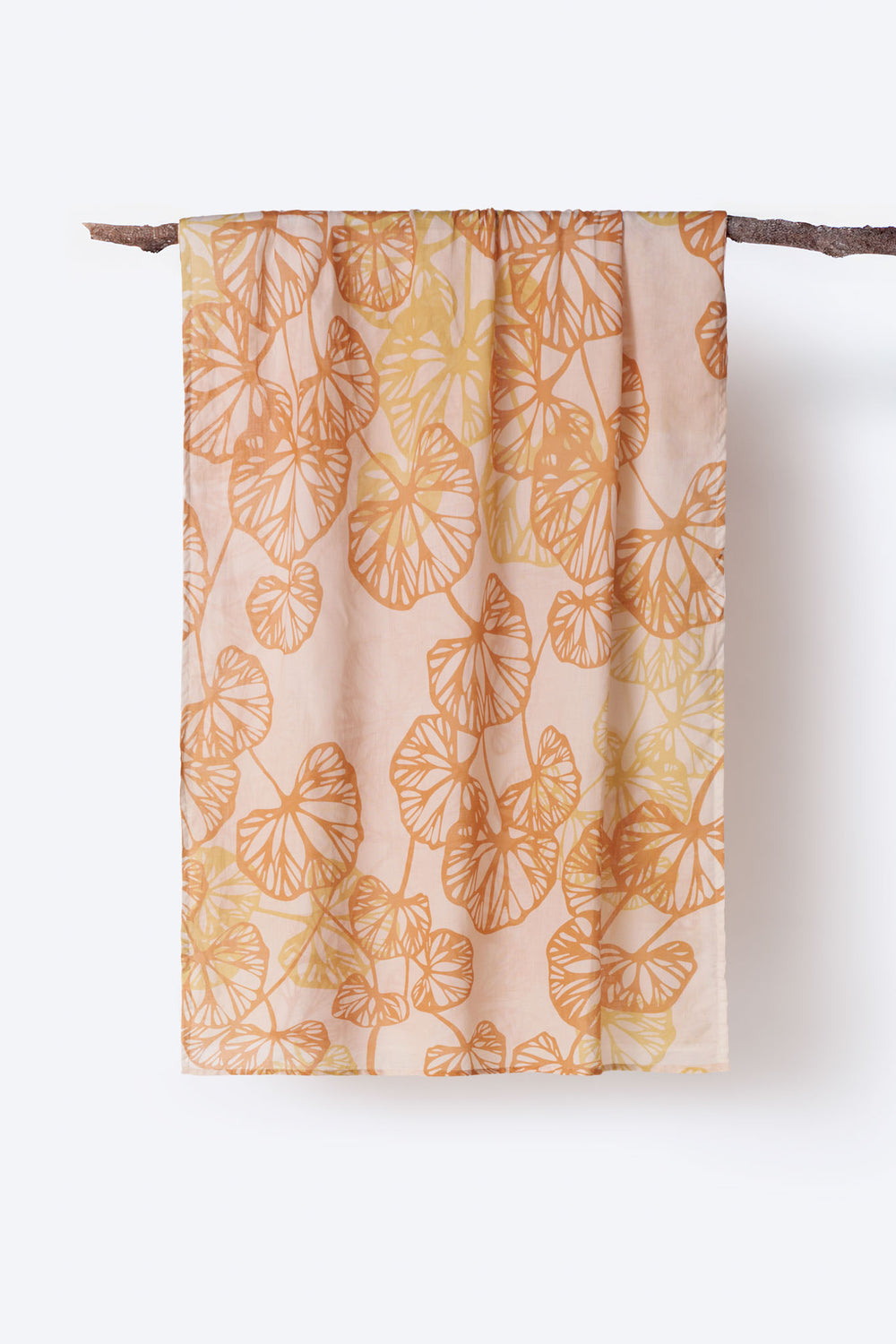 Soft cotton scarf with warm orange and yellow botanical leaf print displayed hanging on branch – airy and breathable accessory with a nature-inspired design, perfect for spring layering