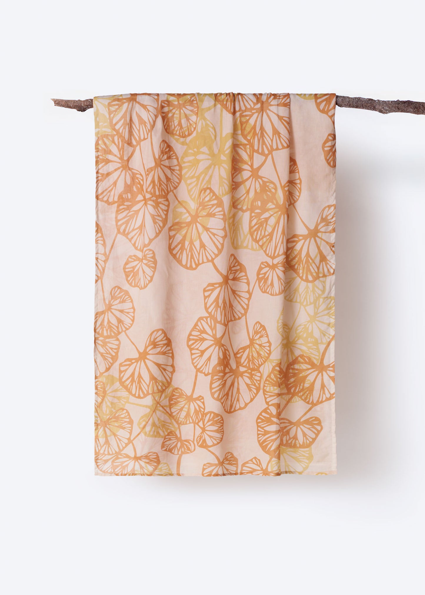 Soft cotton scarf with warm orange and yellow botanical leaf print displayed hanging on branch – airy and breathable accessory with a nature-inspired design, perfect for spring layering