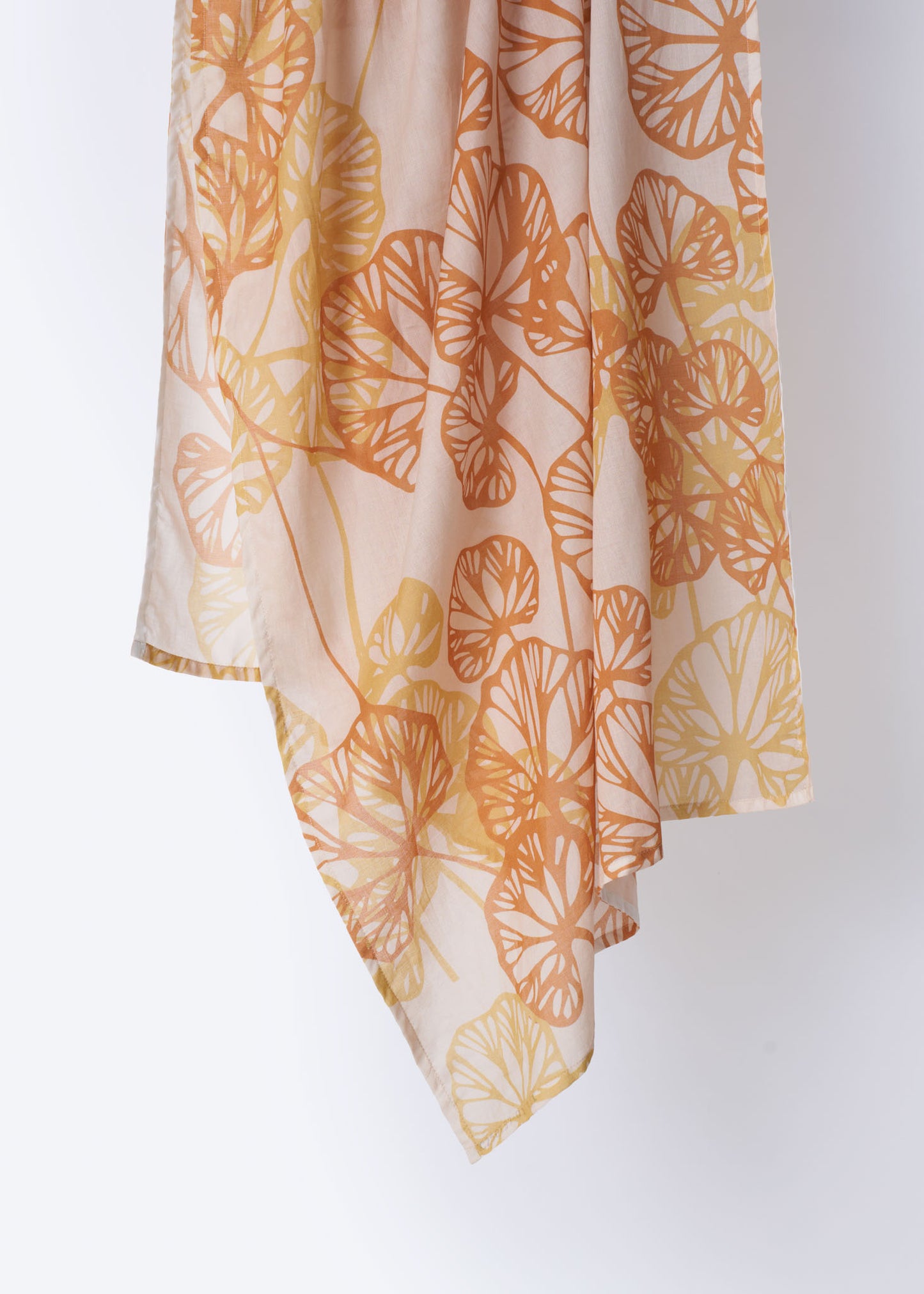 Close-up of soft cotton scarf in blush pink with overlapping orange and yellow leaf silhouettes – lightweight, breathable fabric with a delicate drape, ideal for spring and summer wear
