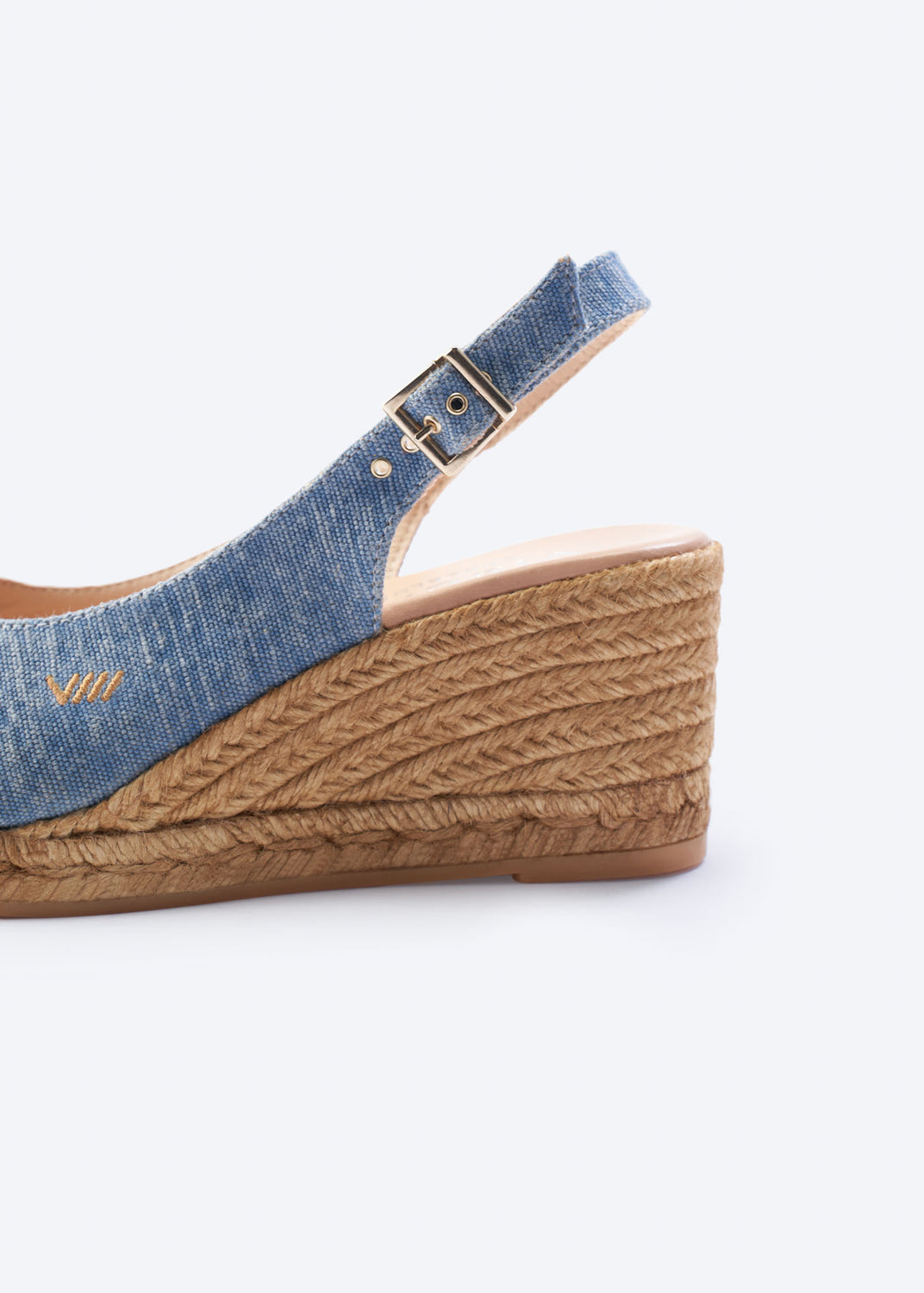 Close-up of washed denim wedge espadrille sandal with slingback strap hardware and a natural braided jute wedge, handcrafted in Spain