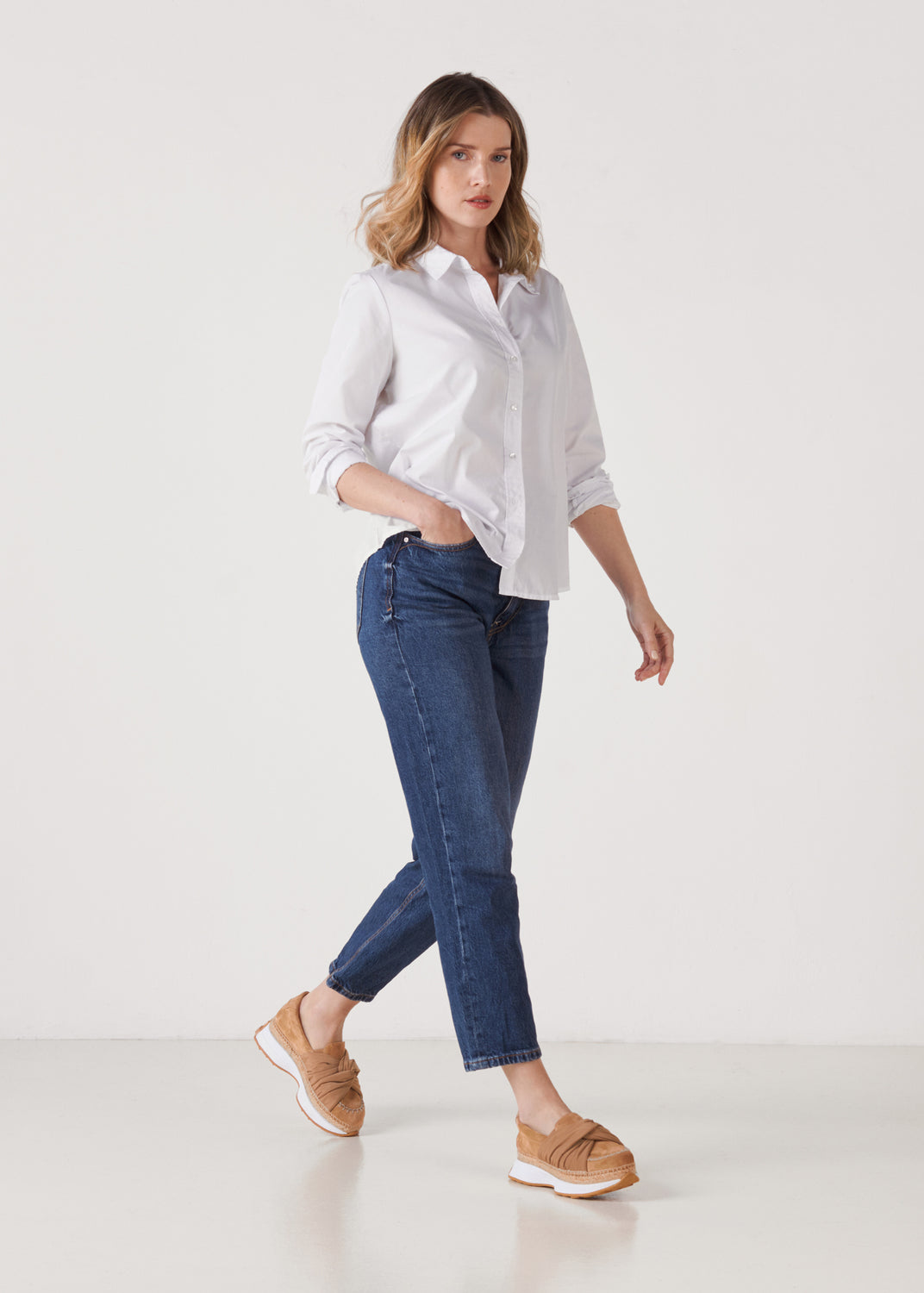 Full-length model wearing camel suede slip-on platform sneakers with a white sole