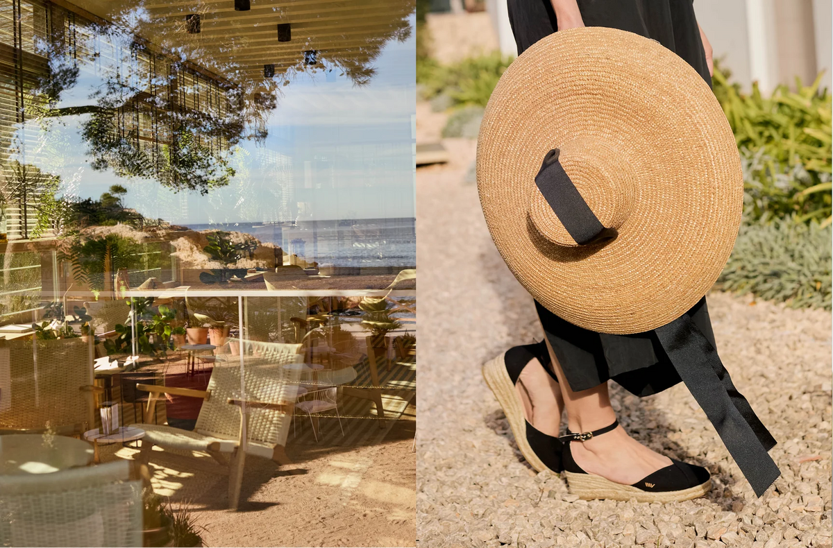 A split lifestyle image showing a straw sun hat with a black ribbon band on the right, held by a person wearing black espadrille wedge sandals and black trousers while walking on a gravel path. The left side shows a reflection of a beachside restaurant patio.