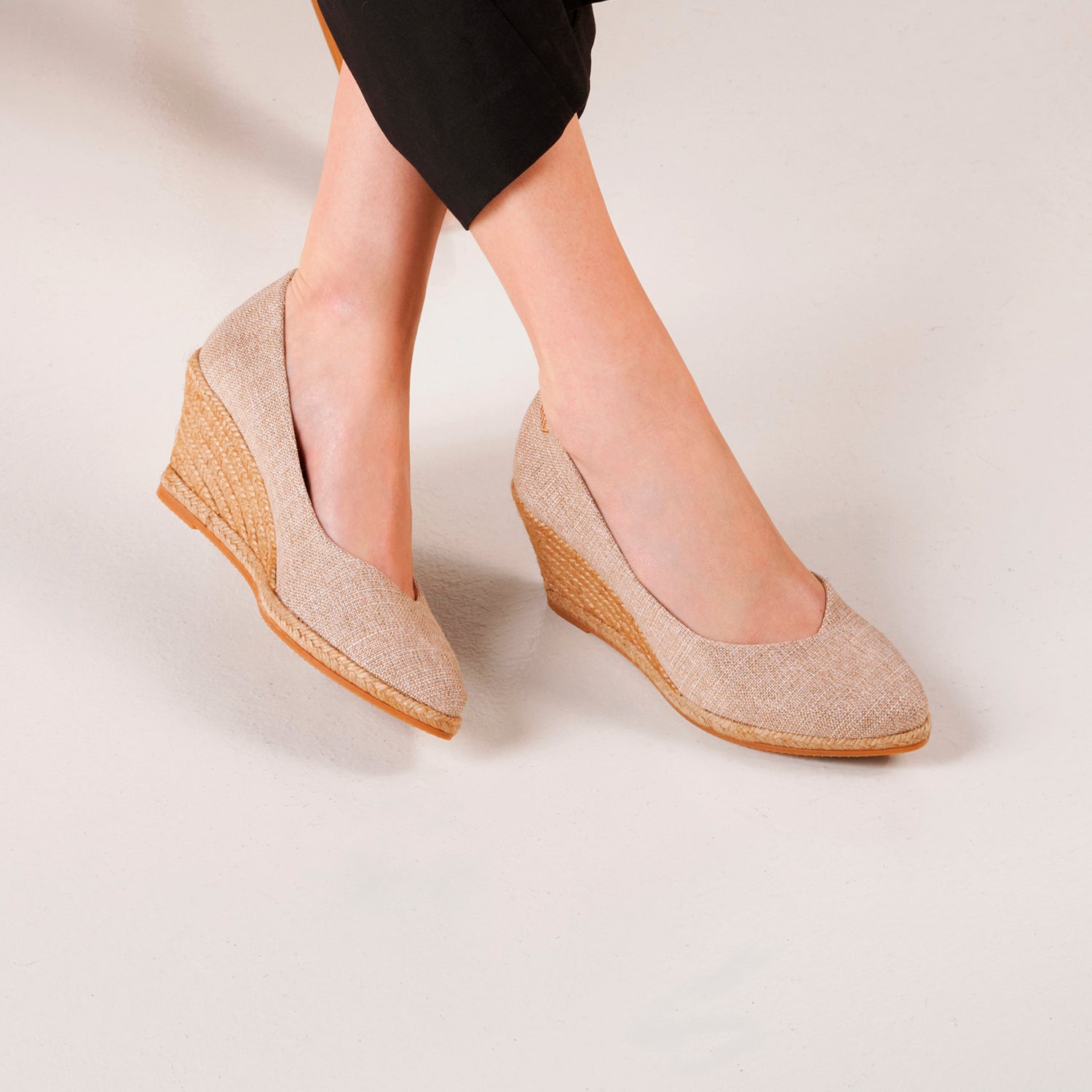 On-foot studio shot of gold espadrille wedge pumps with a braided jute sole