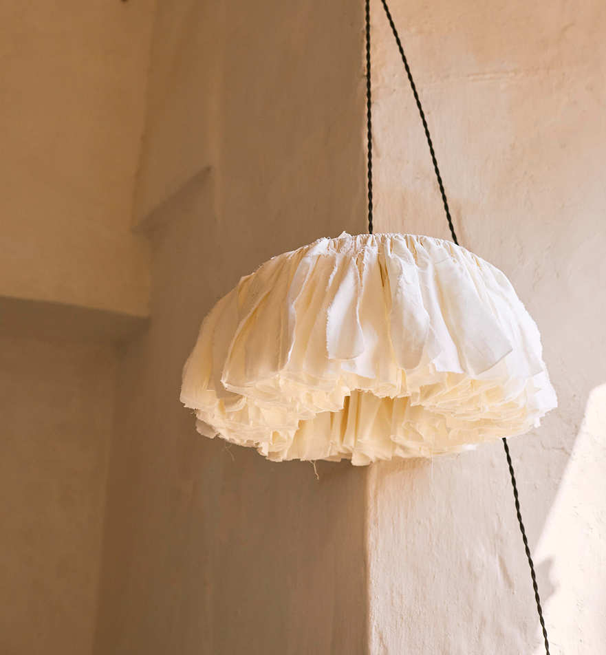 Soft sculptural fabric pendant lamp in a warm Mediterranean interior with natural sunlight.