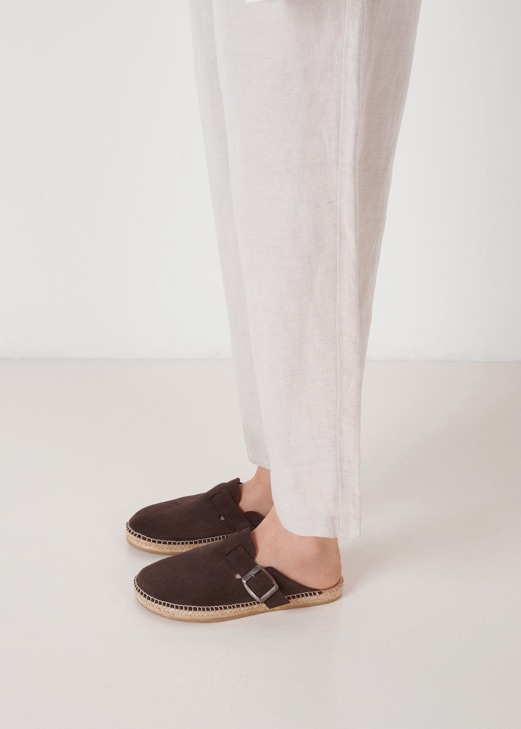 Model wearing brown suede espadrille clogs with buckle, close-up.
