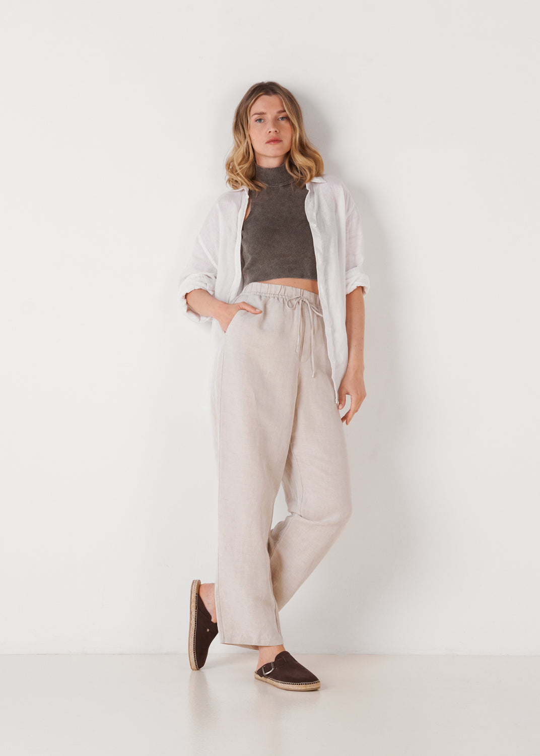 Model standing wearing brown suede espadrille clogs.