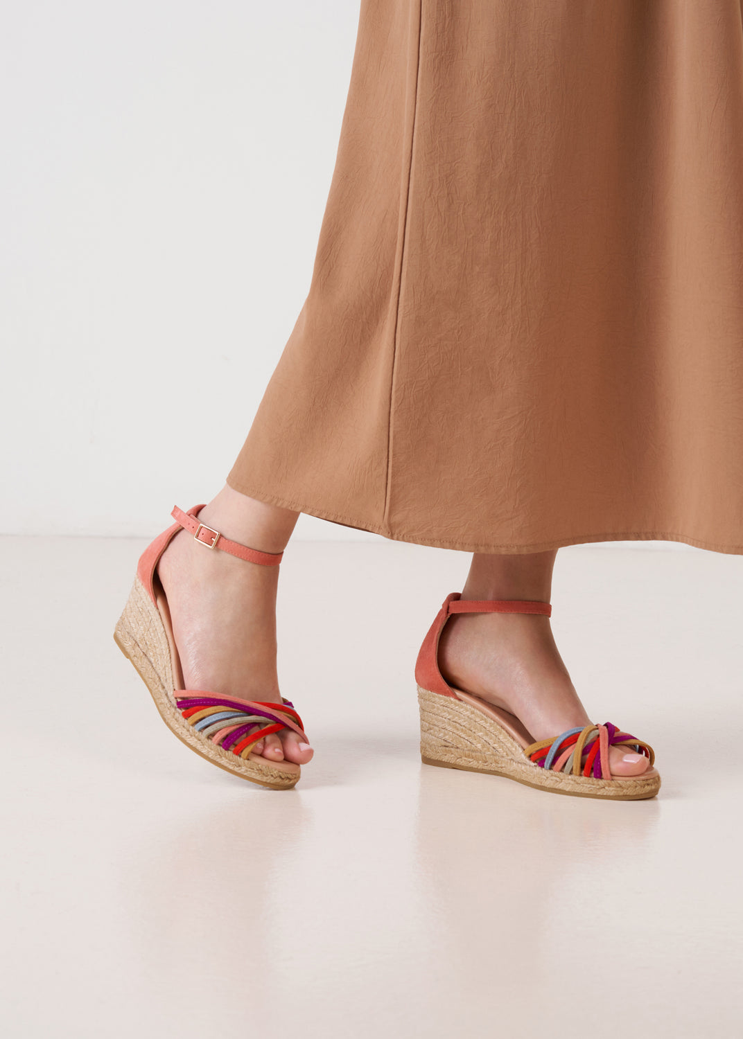 Pink suede ankle-strap wedge espadrille sandals with multicolor straps and a natural jute platform, on model