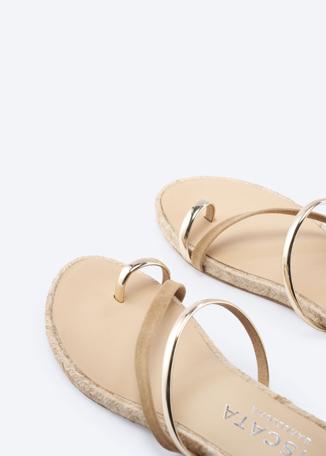 Close-up of camel suede flat sandals with metallic straps.