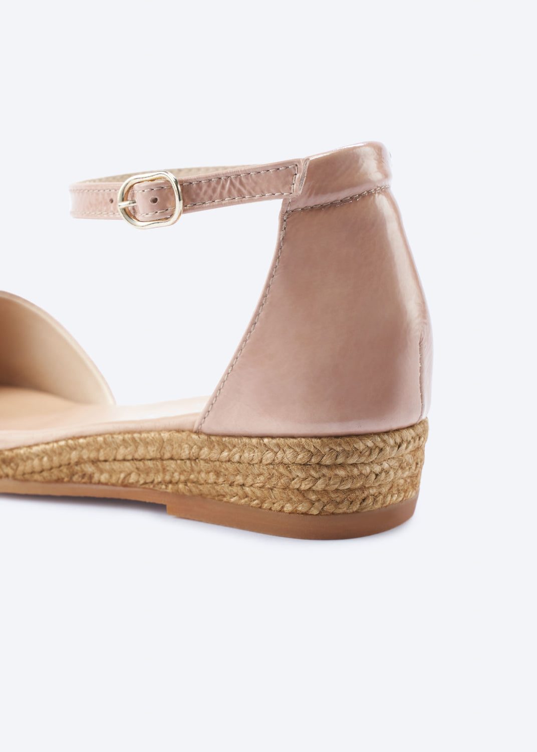 Close-up of pink leather espadrille flat highlighting ankle strap buckle and braided jute sole.