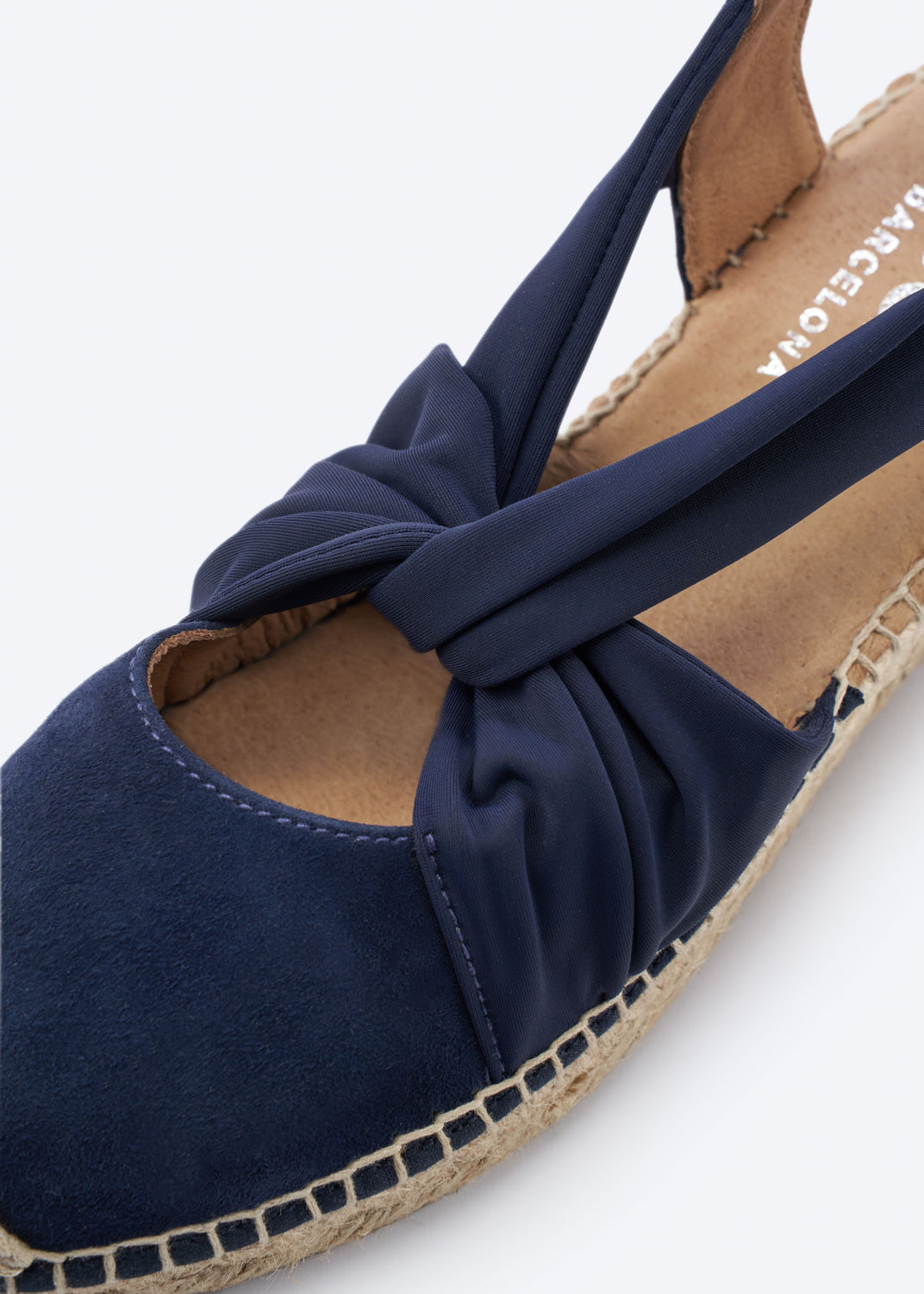 Close-up of a navy suede espadrille wedge with knot strap detail.