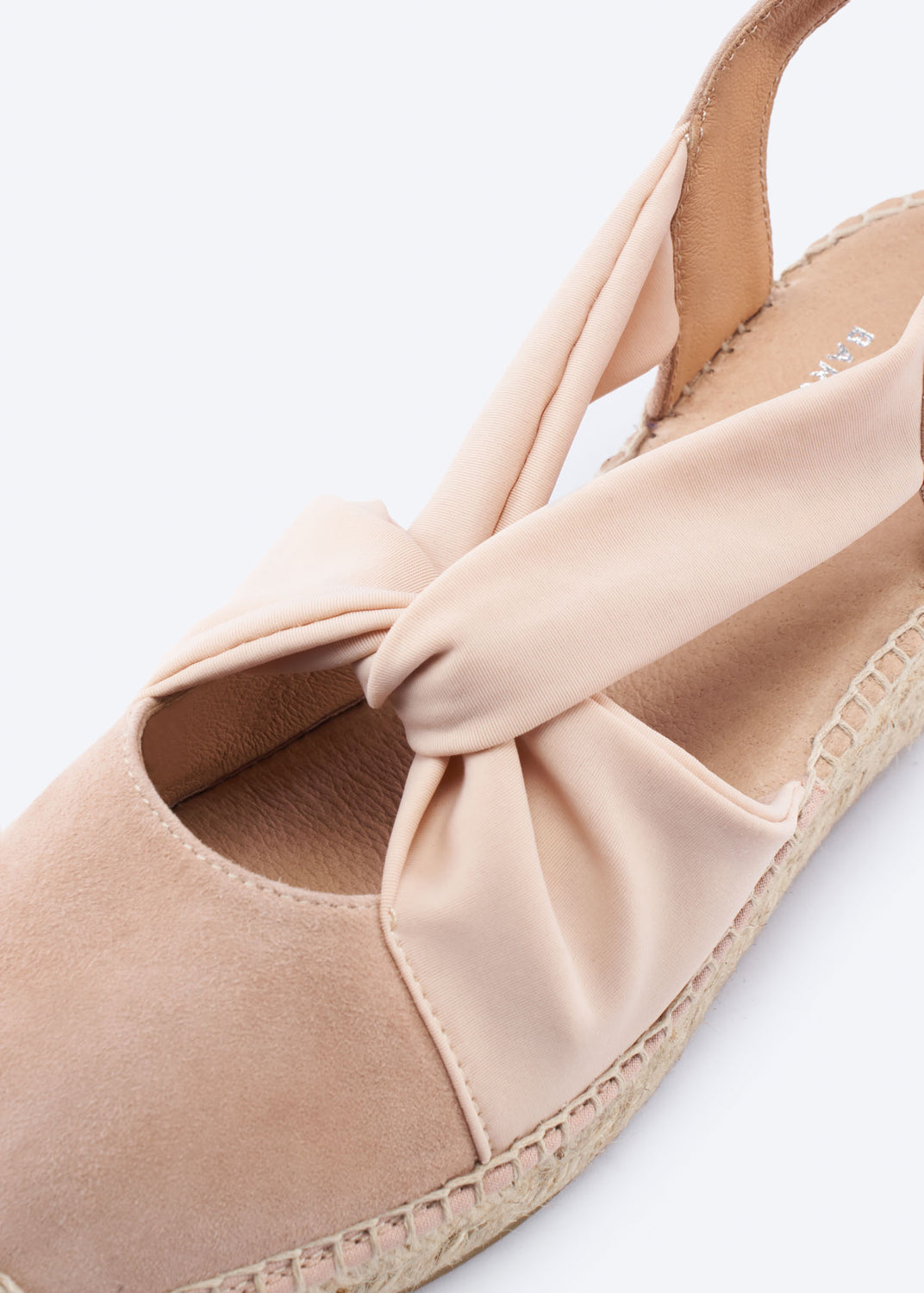 Close-up of a nude suede espadrille wedge with knot strap detail.