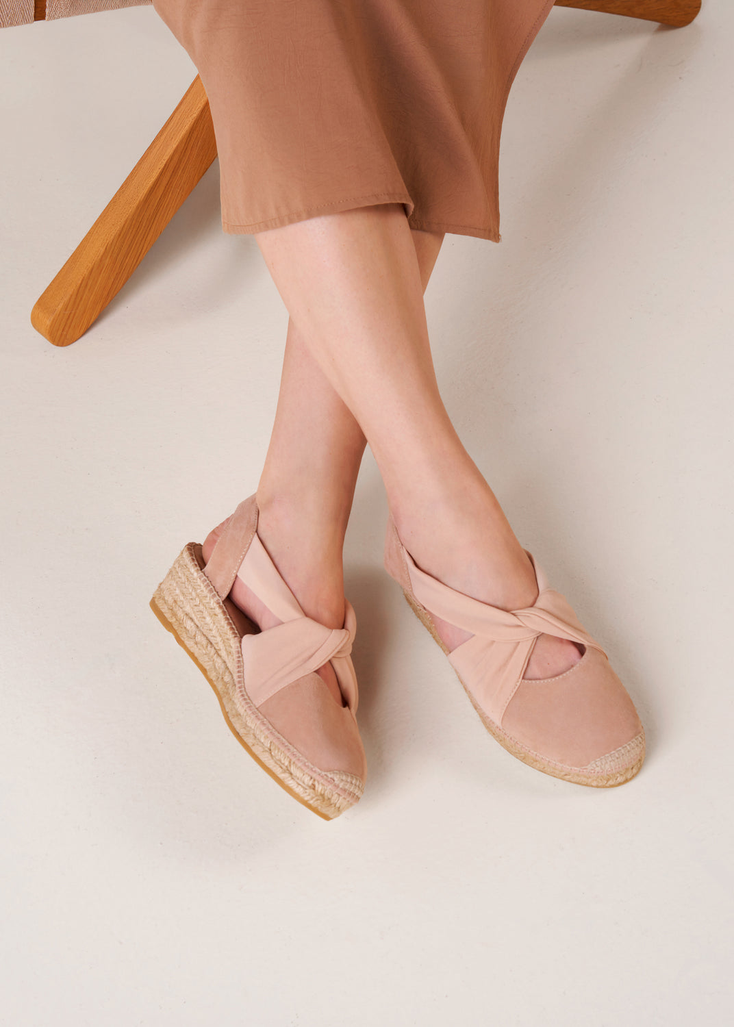 Close-up of nude suede slingback espadrille wedges worn on feet.