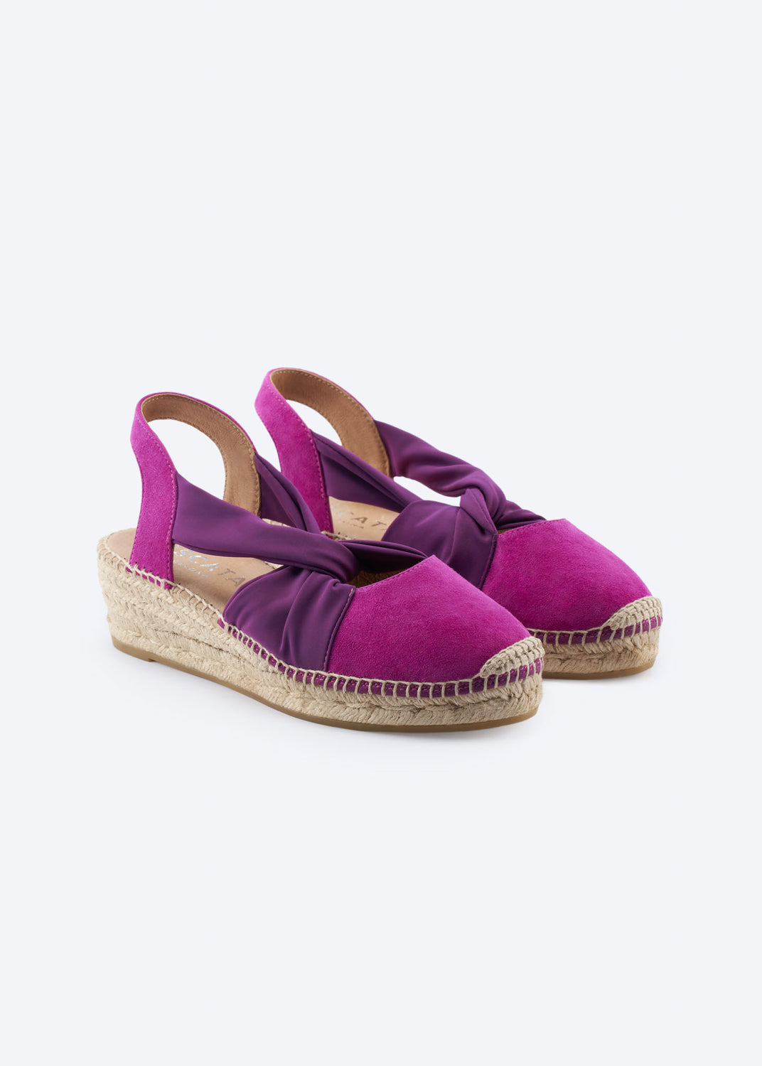 Pair of fuchsia suede slingback espadrille wedges with purple knot strap.