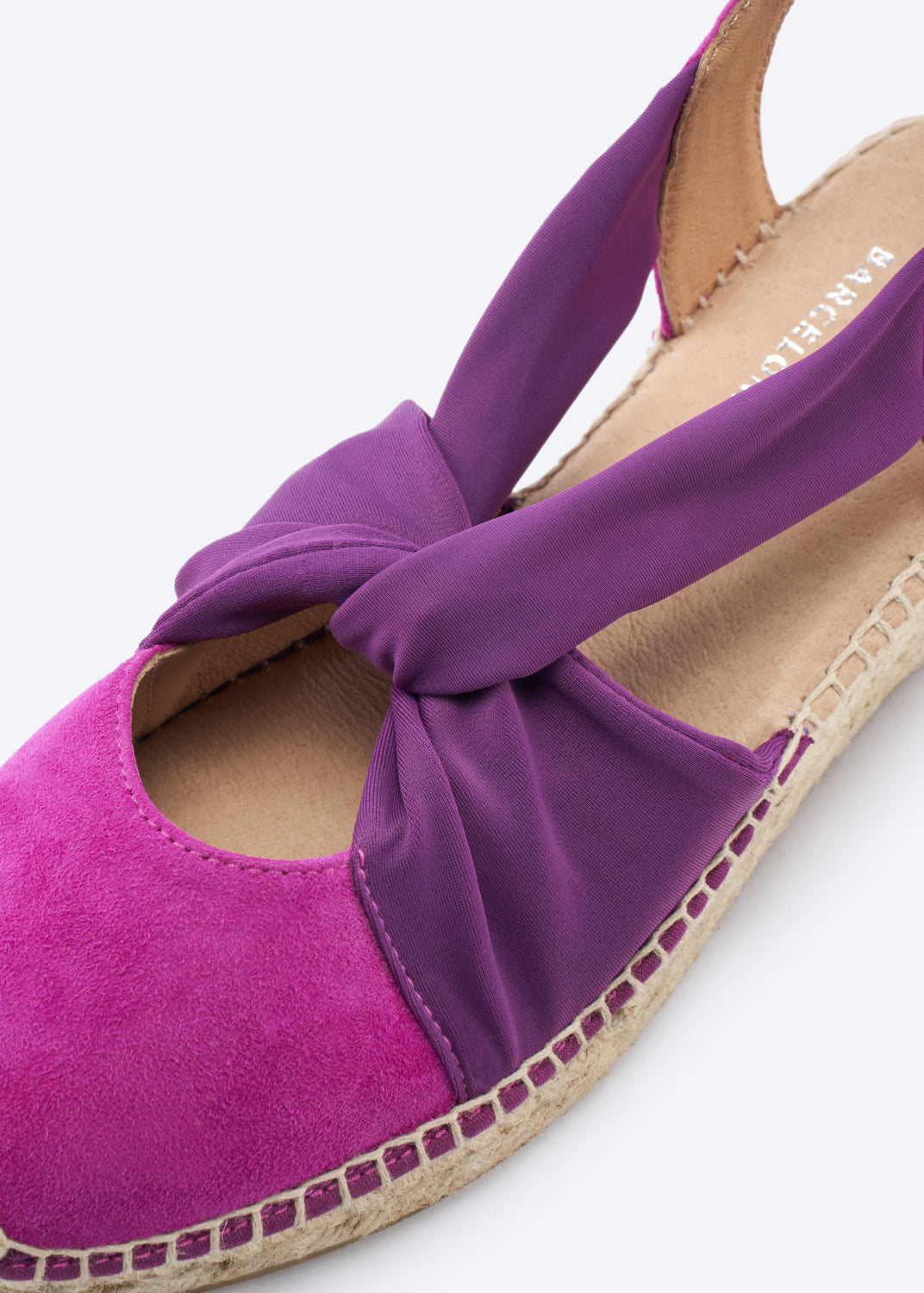 Detail of the knot strap on a two-tone espadrille wedge in fuchsia and purple.
