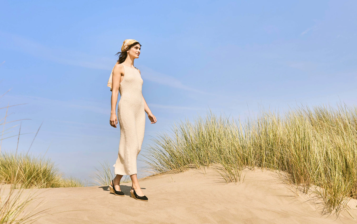 Black espadrille wedge sandals with ankle straps styled on sandy dunes for an effortless summer escape