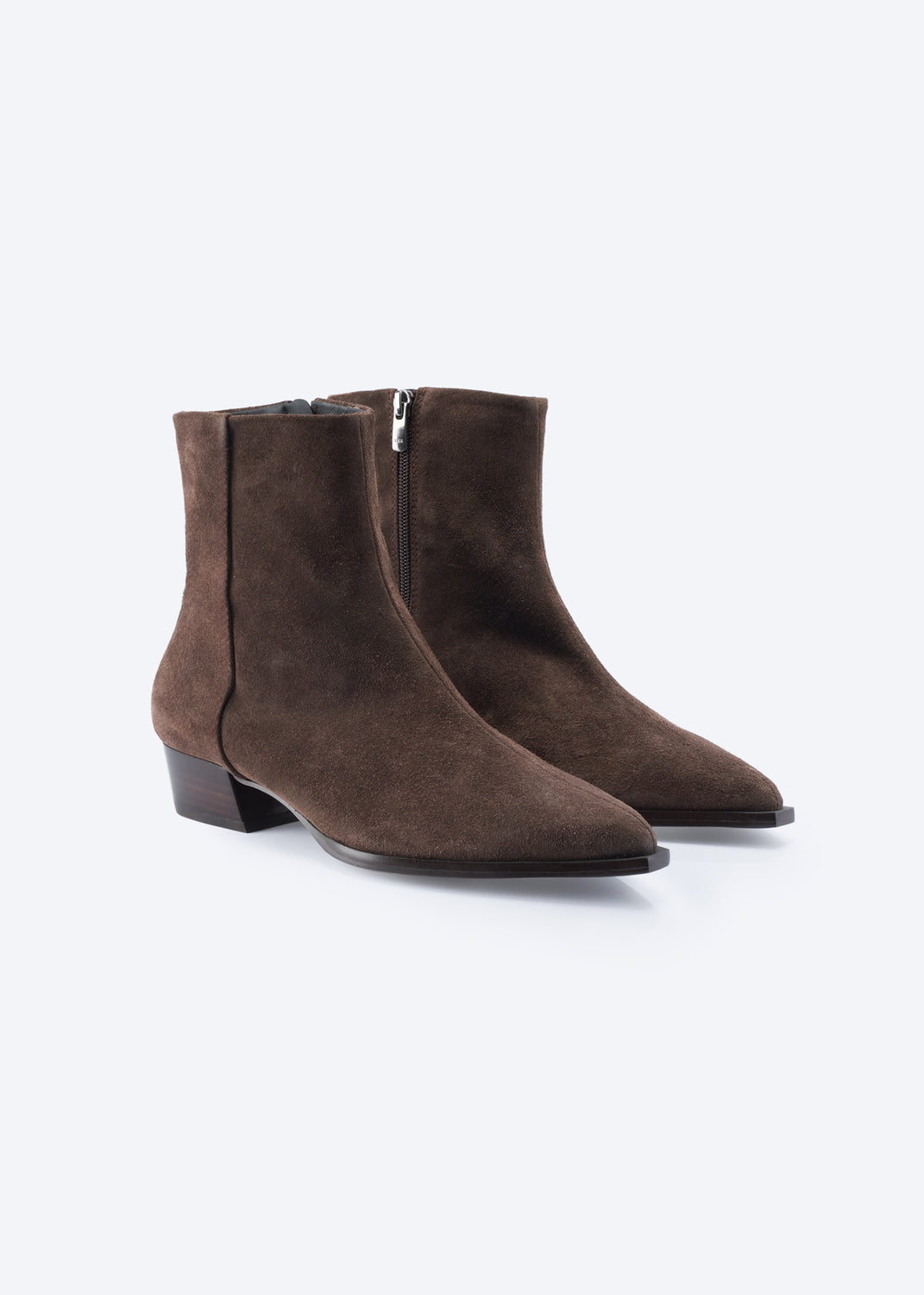 A pair of dark brown suede ankle boots with pointed toes and low block heels, shown from a three-quarters angle on a light gray background.