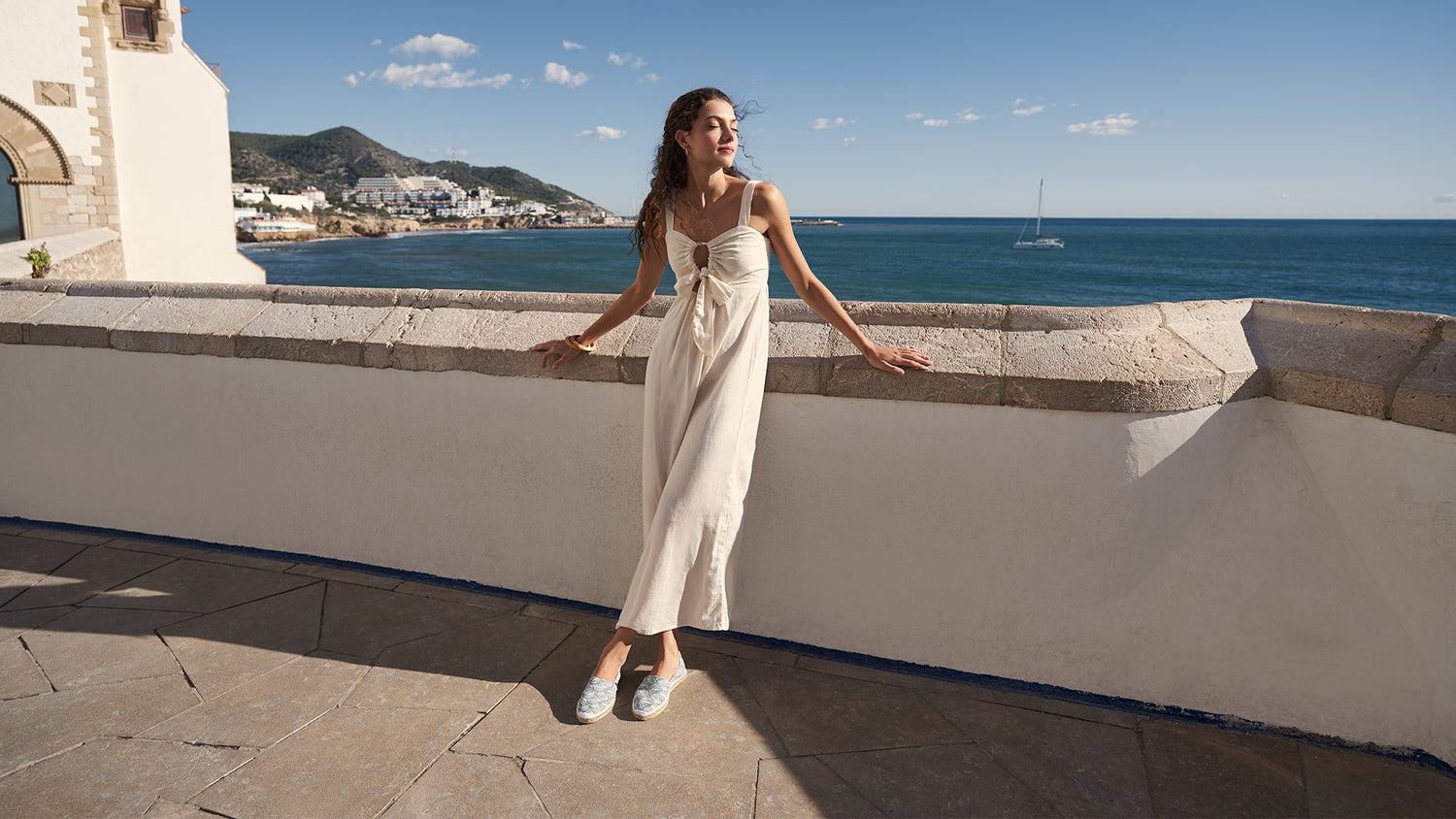 Woman by the sea wearing a beige jumpsuit paired with Llafranc wave pattern espadrille flats