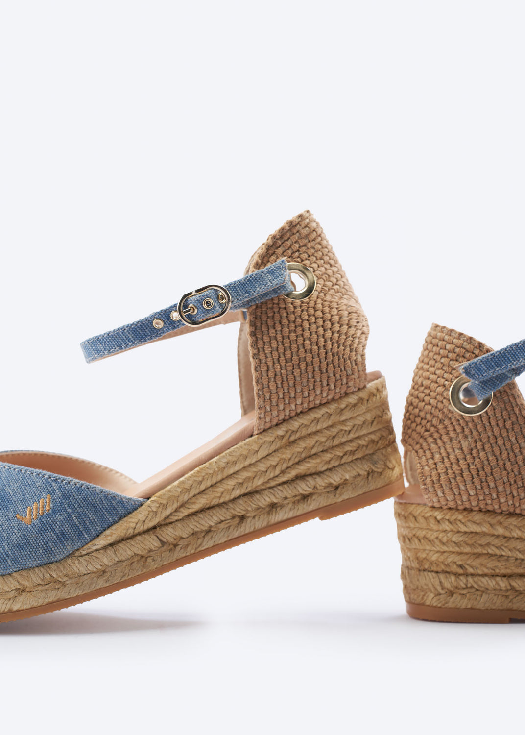 Close-up of washed denim low wedge espadrille with ankle strap hardware and a natural braided jute wedge, handcrafted in Spain