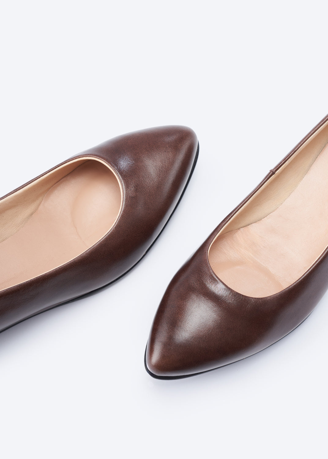 A pair of dark brown leather pointed-toe pumps shown from a top-down angle on a clean white background.