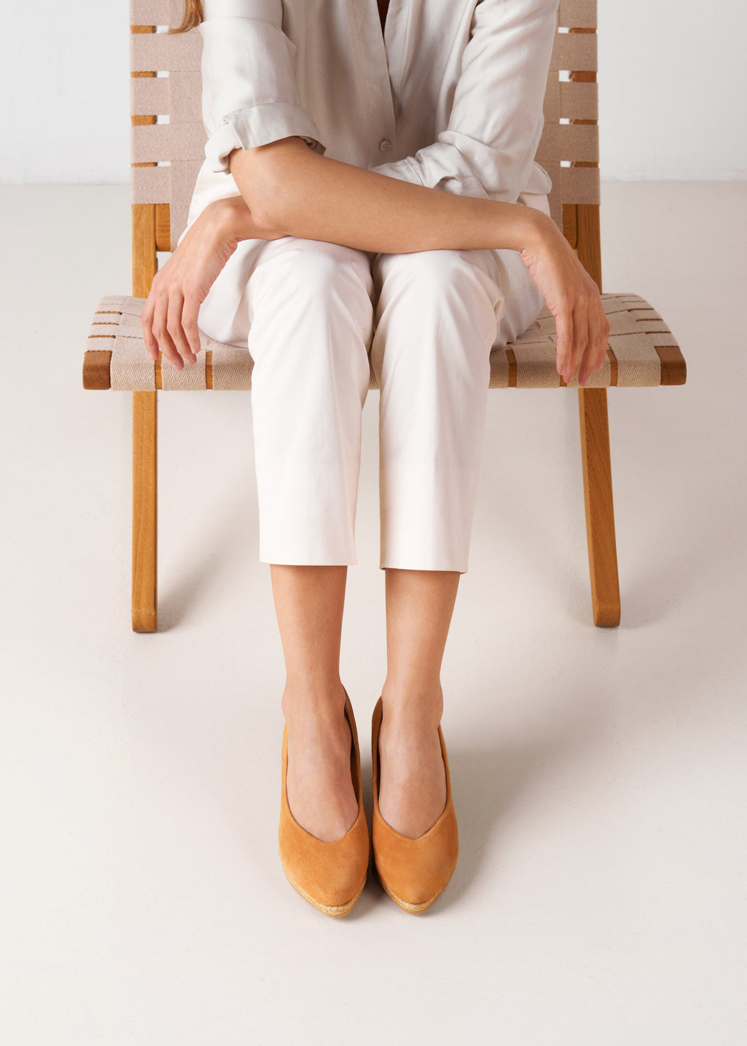Top view of camel suede slip-on wedge espadrilles with a natural jute sole, styled with white pants