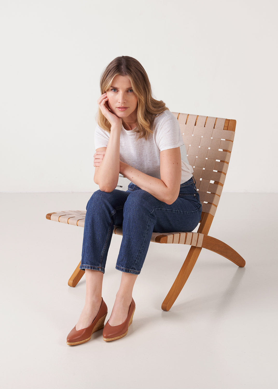 Model seated wearing brown leather espadrille wedge pumps.