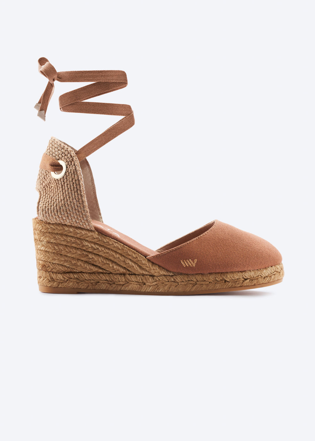Side view of a tan espadrille wedge sandal with wraparound ankle ties, a closed toe, and natural braided jute heel, handcrafted in Spain