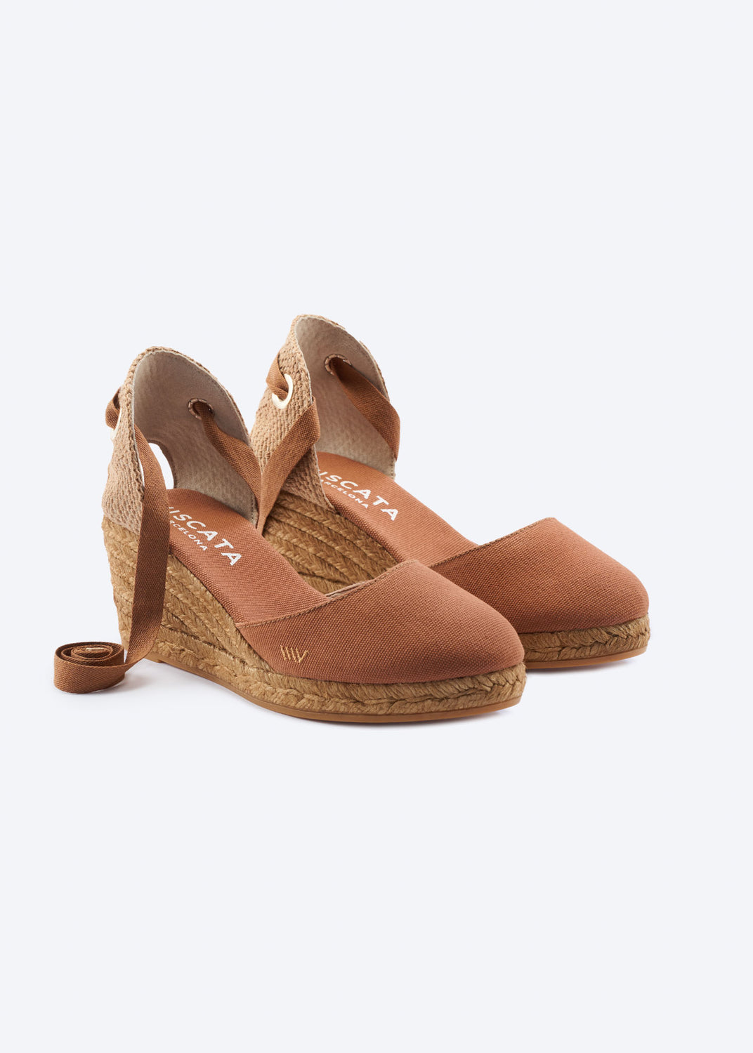 Tan wedge espadrille sandals with wraparound ankle ties, a closed toe, and natural braided jute wedge, handcrafted in Spain