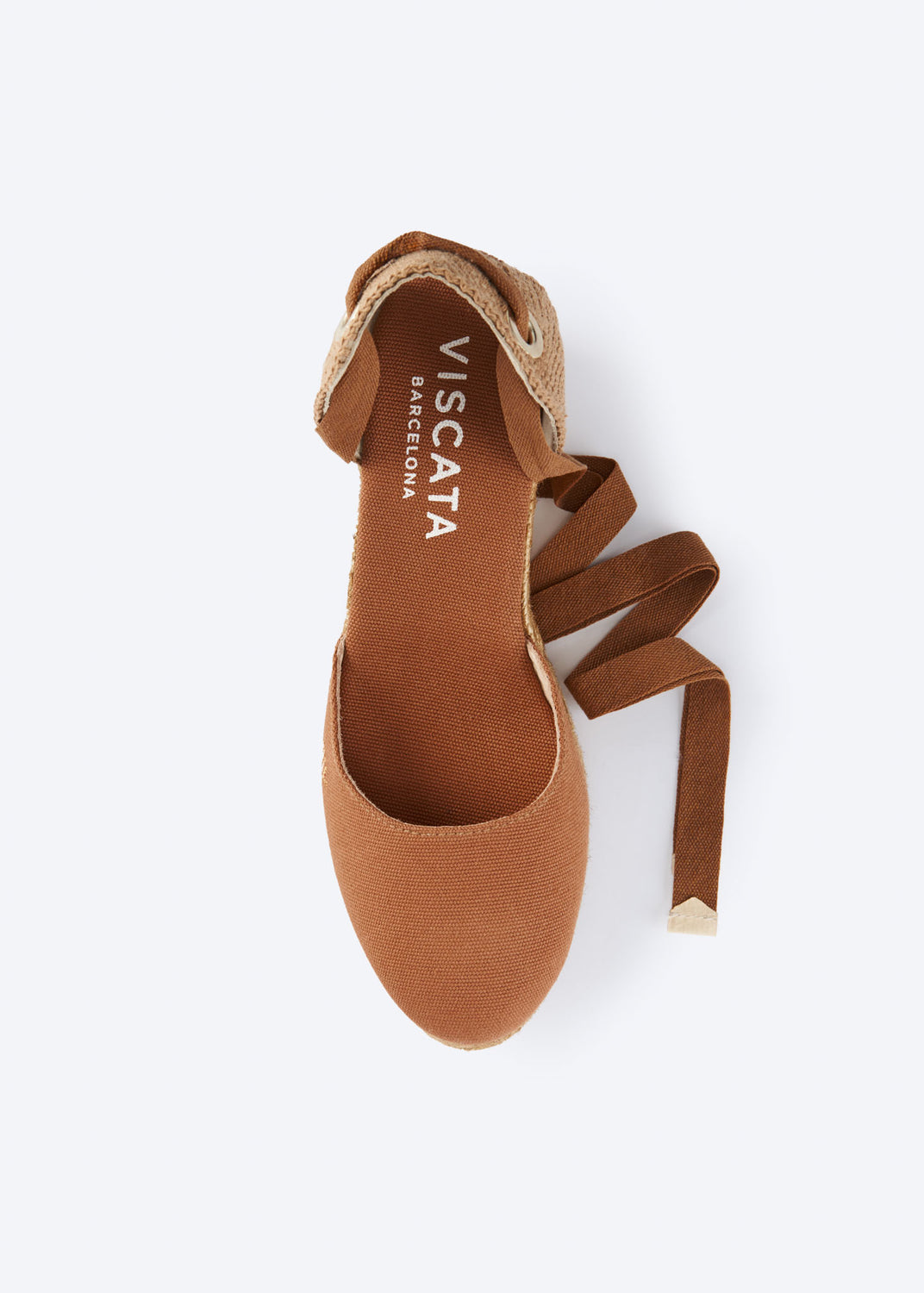Top view of a tan espadrille sandal with wraparound ankle ties and a closed toe, handcrafted in Spain