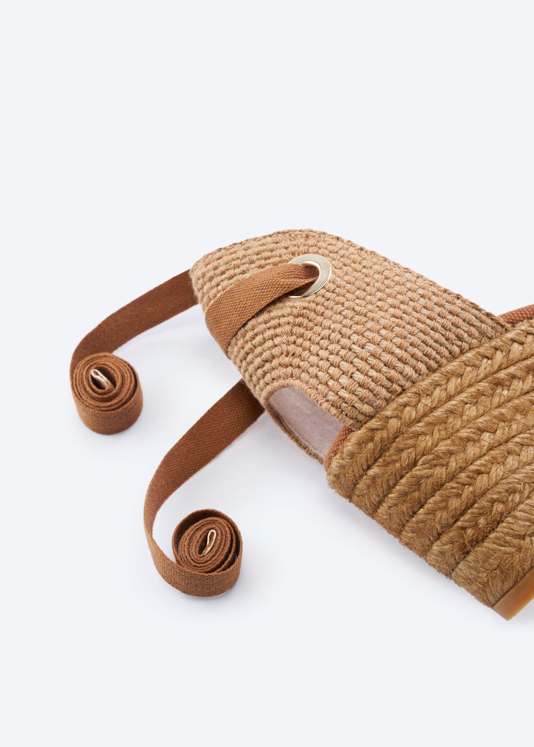 Close-up of a tan espadrille wedge heel with wraparound ankle ties and a natural braided jute finish, handcrafted in Spain