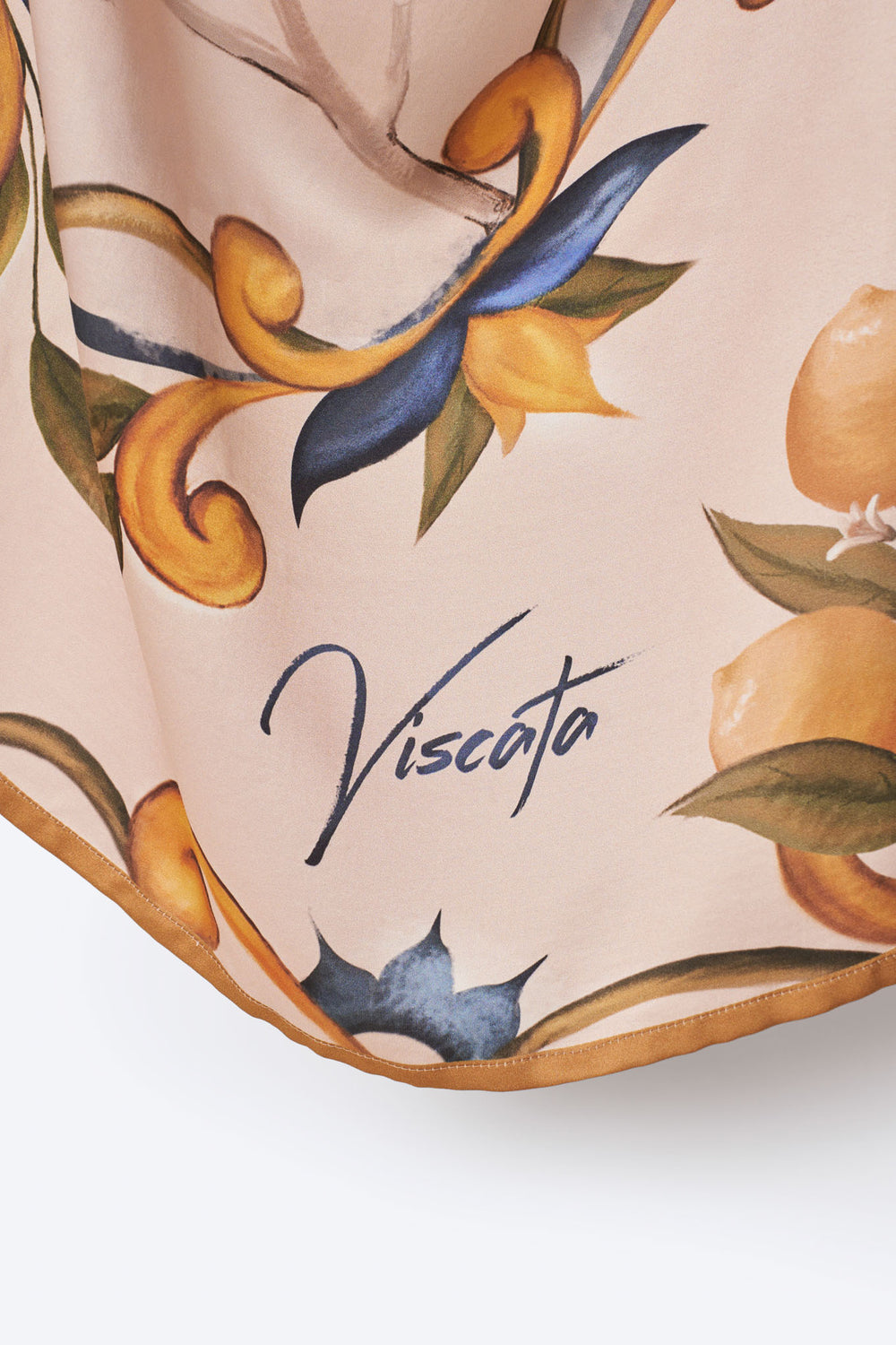 Close-up of Viscata square scarf corner featuring brand signature and hand-painted Mediterranean lemon and floral motif – premium detailing on soft blush fabric for an elegant designer finish