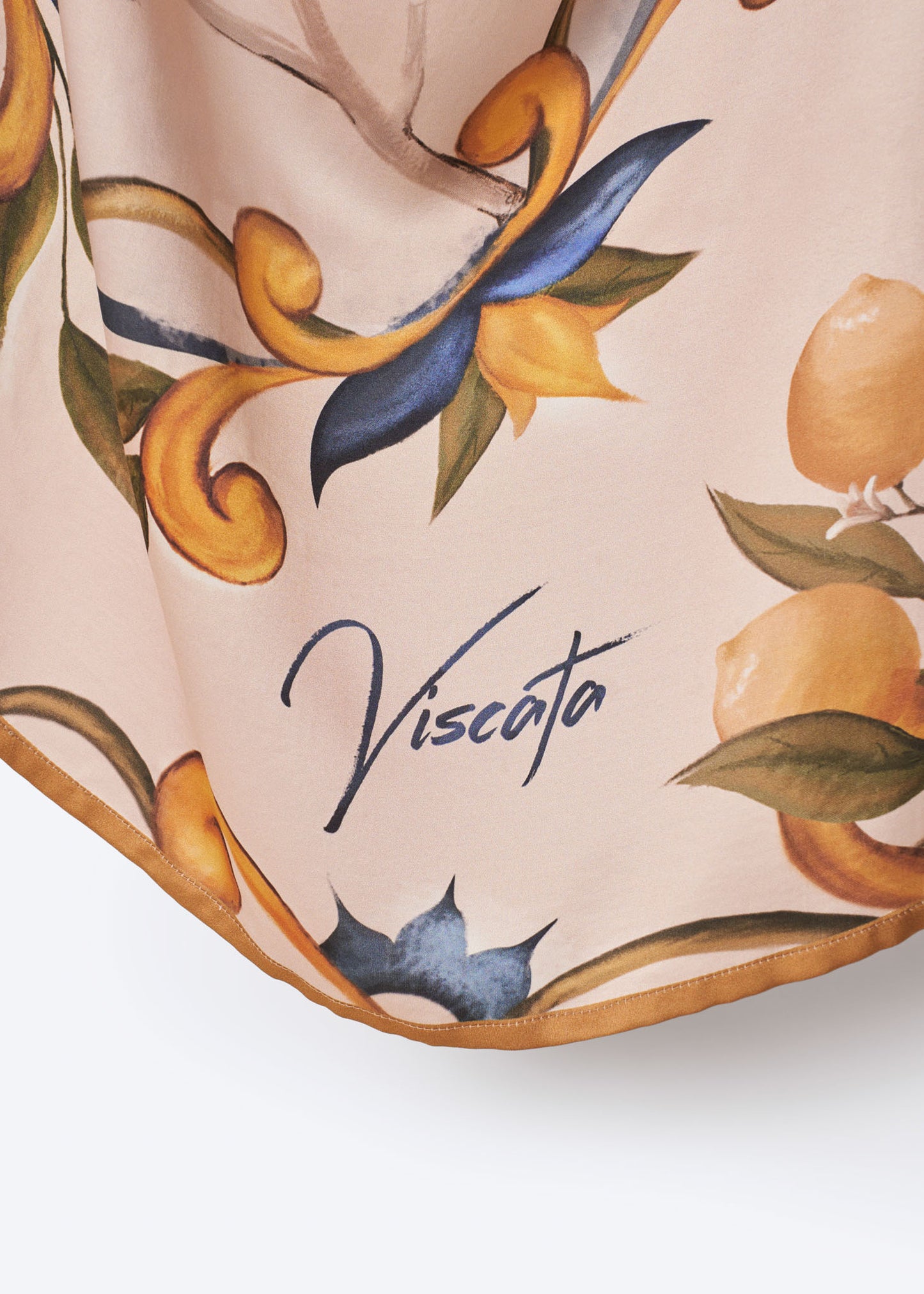 Close-up of Viscata square scarf corner featuring brand signature and hand-painted Mediterranean lemon and floral motif – premium detailing on soft blush fabric for an elegant designer finish