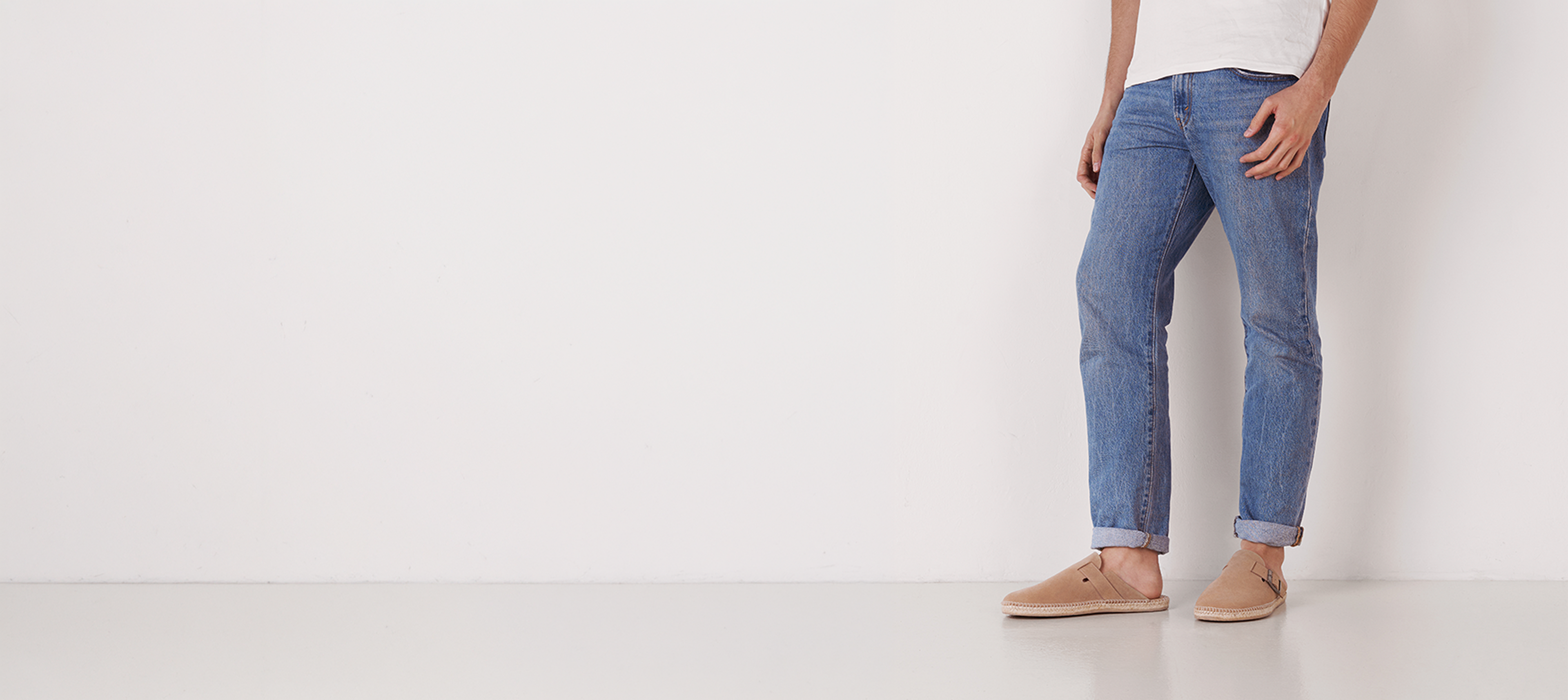 Person wearing blue jeans standing against a white background